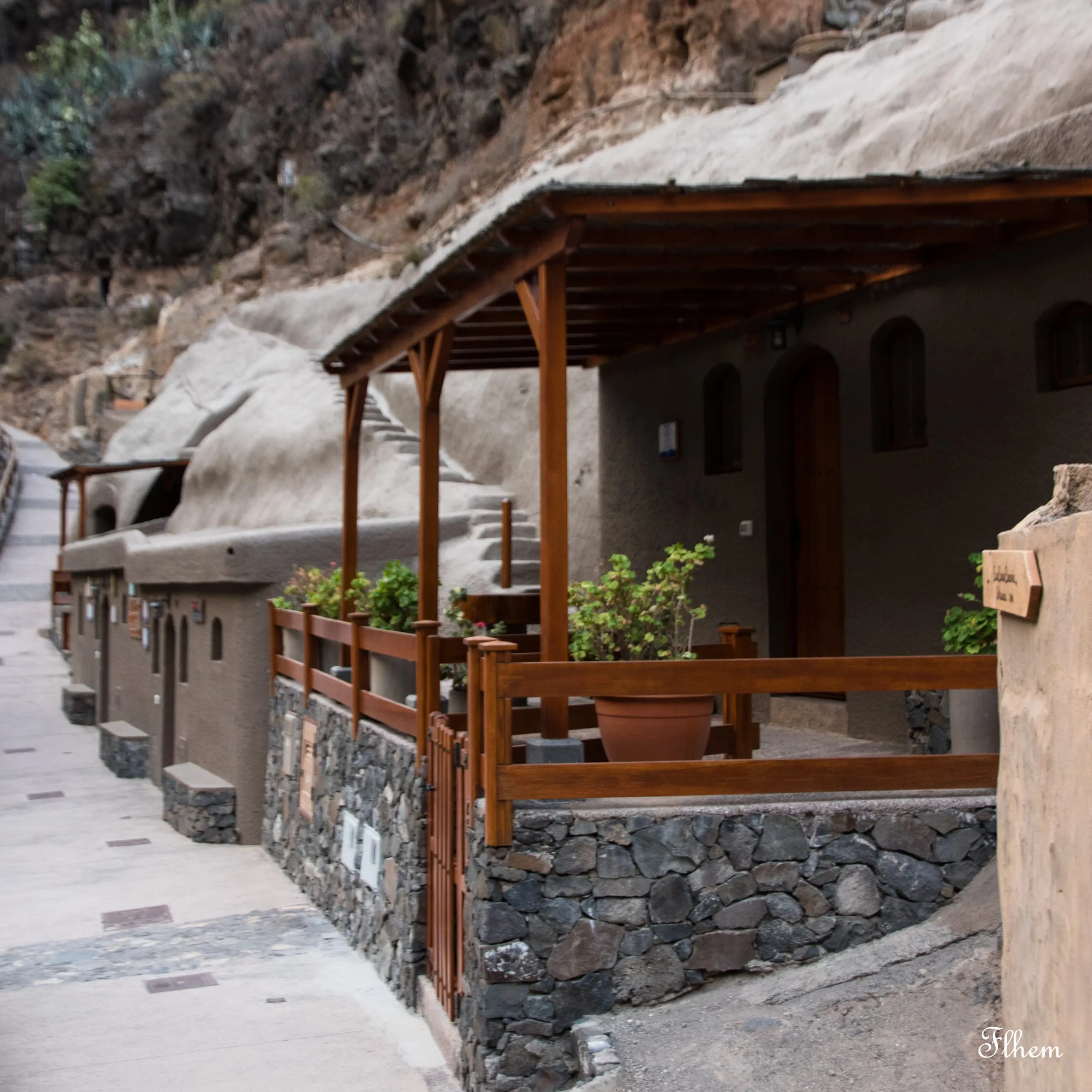 Ruelle de maisons troglodytes avec une terrasse en bois et des plantes en pot